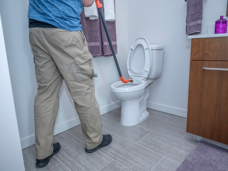 Plumber using toilet Auger for blocked toilet